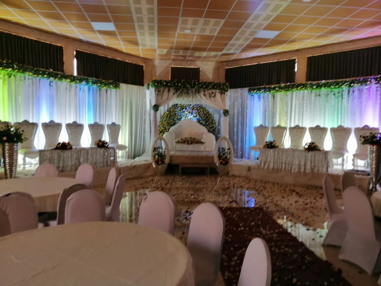 Hall set for an event with white chairs, flowers and coloured lighting