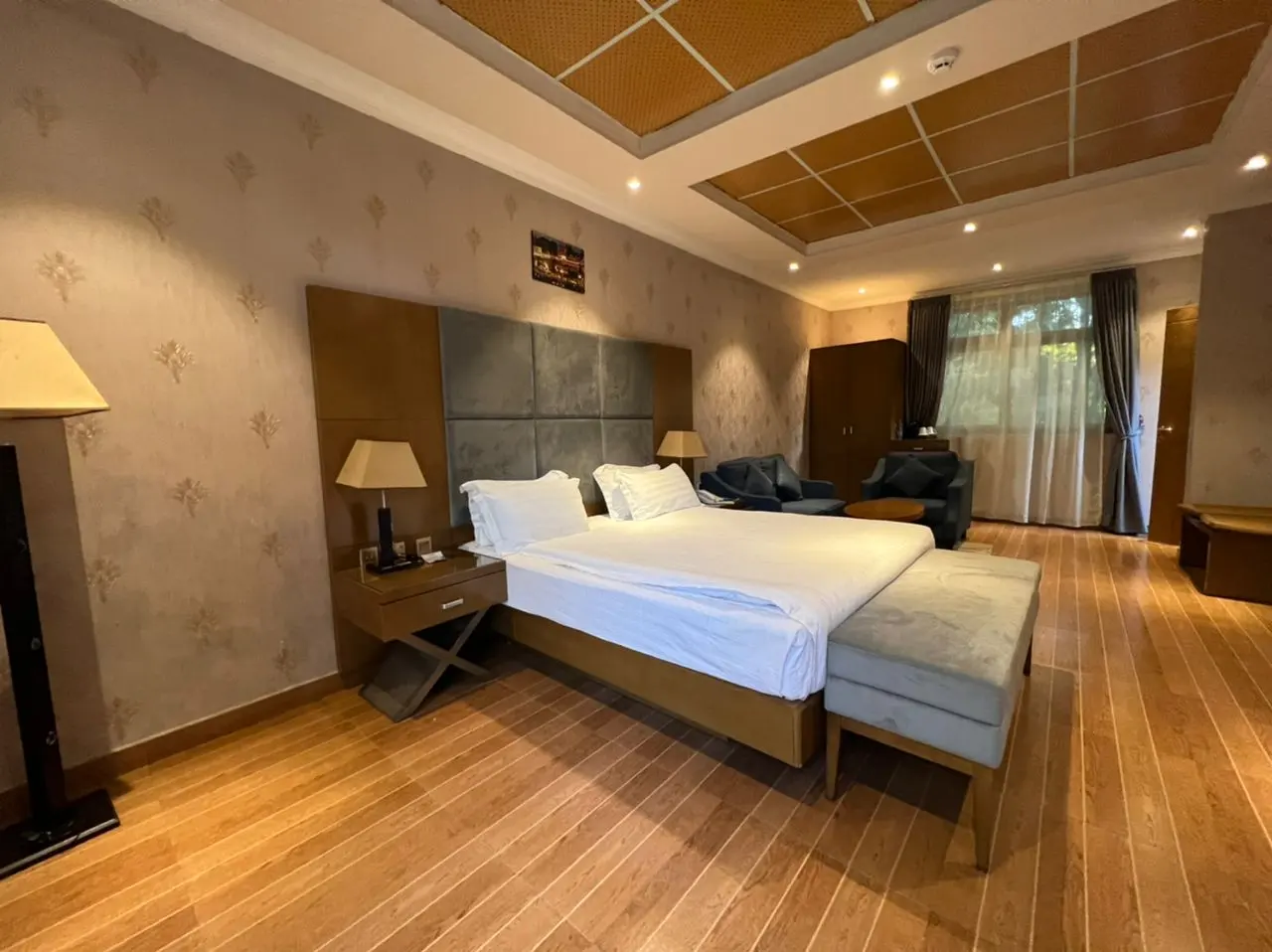 Semi-suite bedroom with a king bed, a grey headboard and a wooden floor