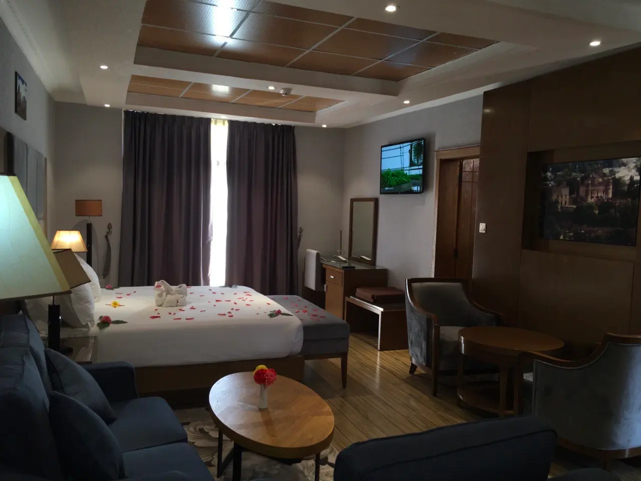 Suite bedroom with a bed dressed with rose petals, a sofa and a round coffee table