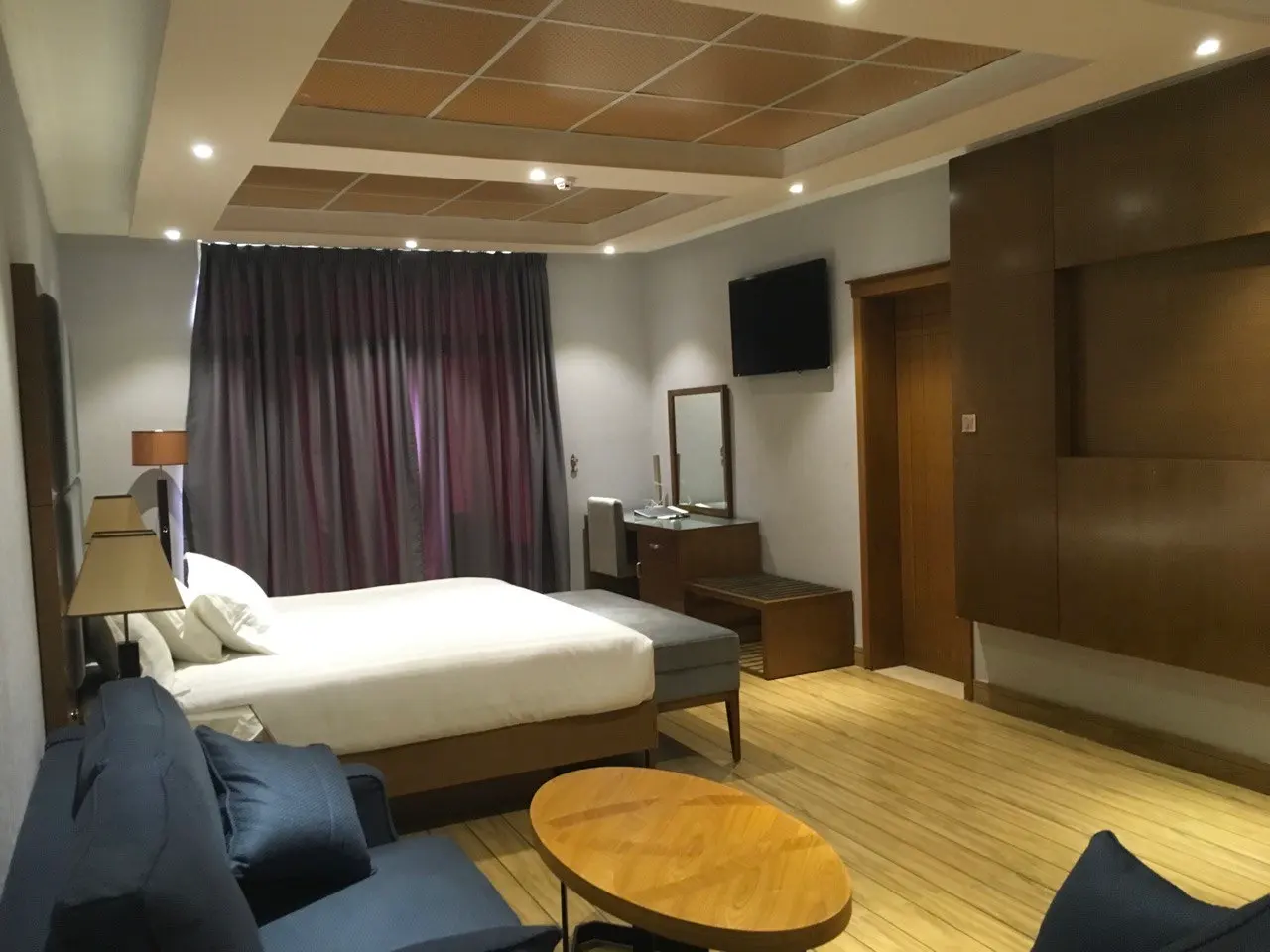 Bedroom with a large bed, a panelled ceiling, curtains and a sofa