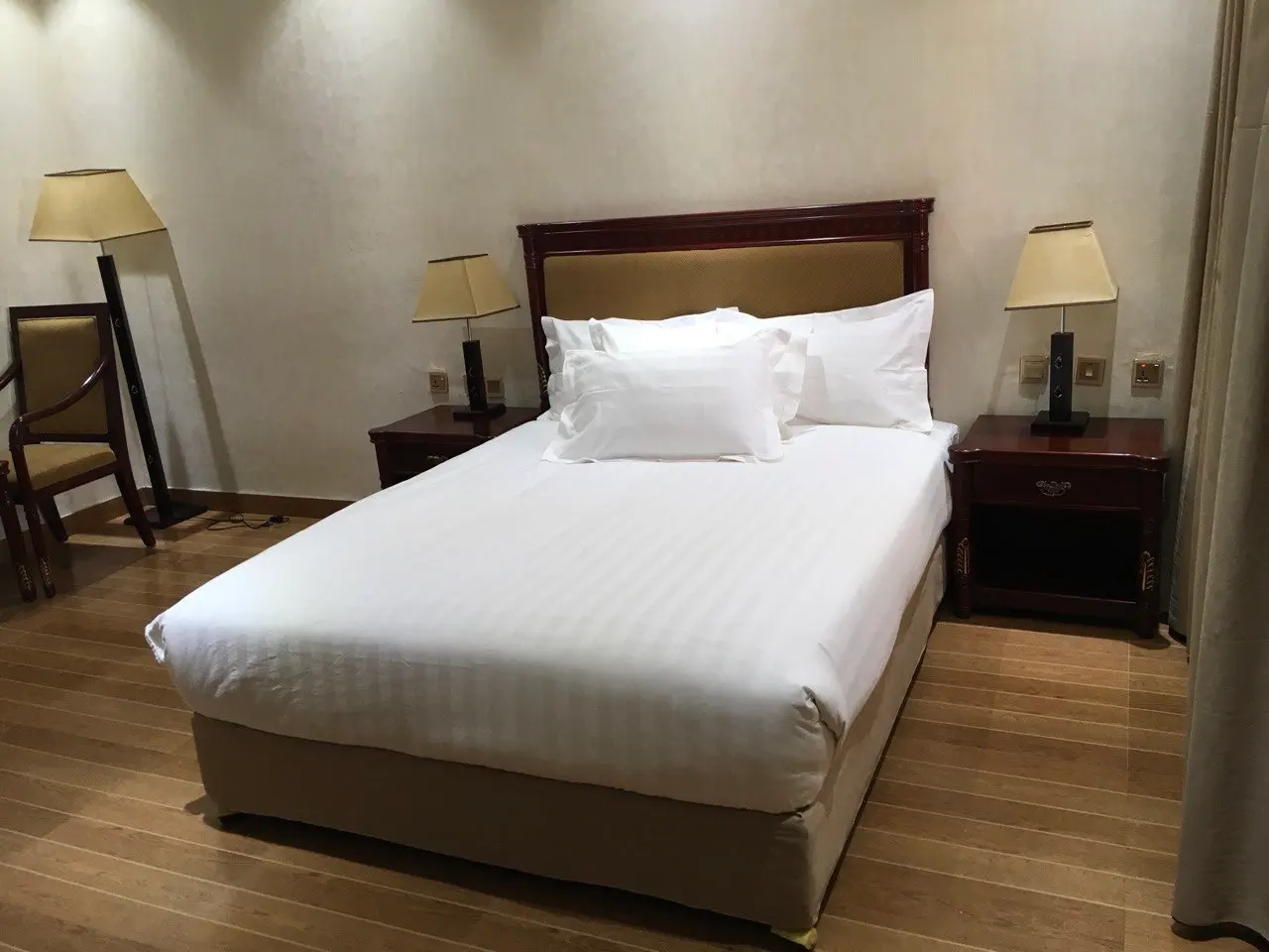 Standard room with a double bed, bedside lamps and a chair