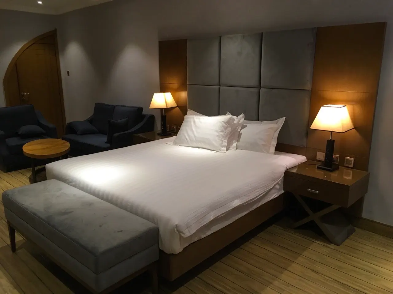 Suite bedroom with a large bed, a grey upholstered headboard and a seating area