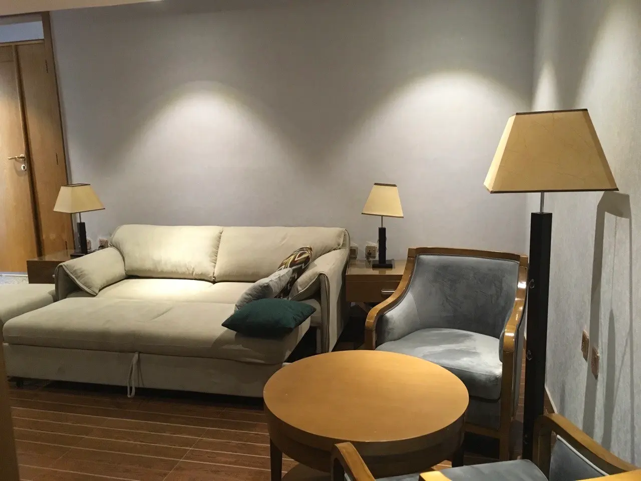 Suite sitting area with a cream sofa bed, armchairs and a round wooden table