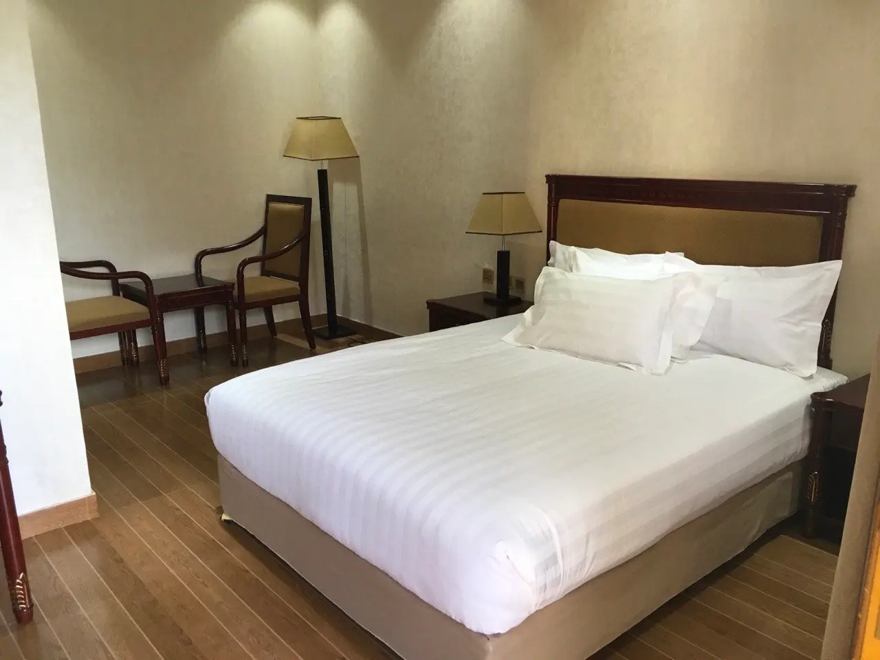 Standard room with a double bed and two wooden armchairs
