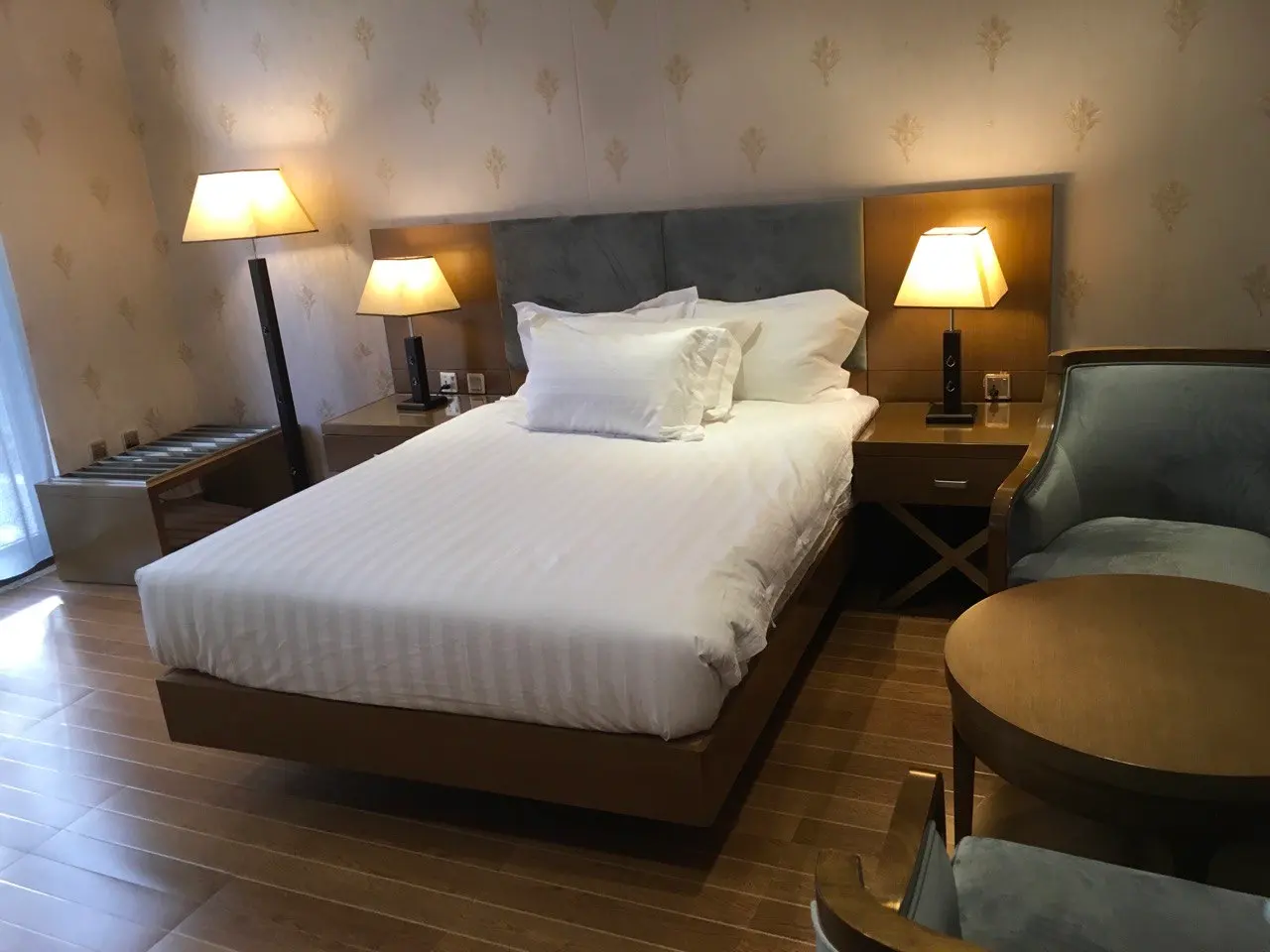 Semi-suite bed with white linen, two lamps and an armchair